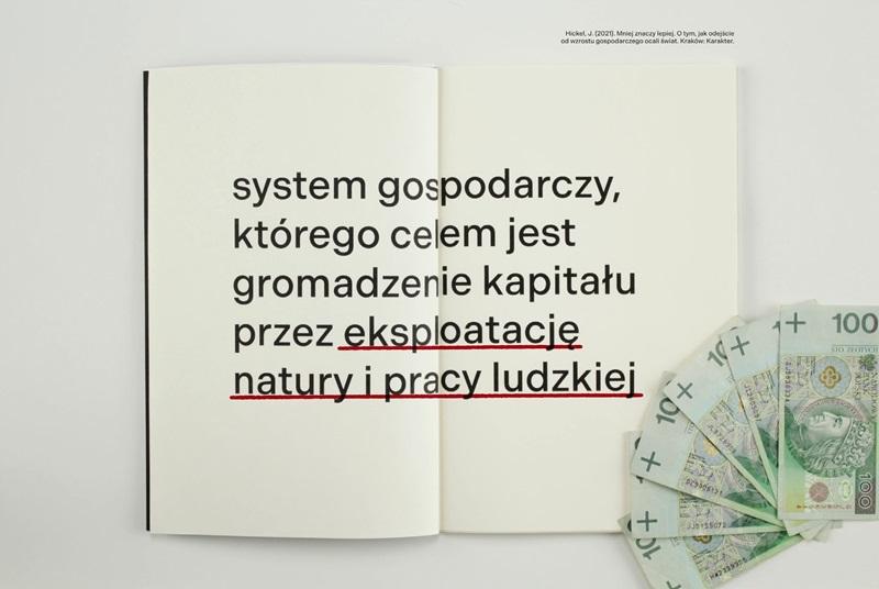 Klatka z filmu. Otwarta książka z napisem: System gostpodarczy którego celem jest gromadzenie kapitału przez eksploatację natury i pracy ludzkiej. Obok leży kilka banknotów stuzłotowych 