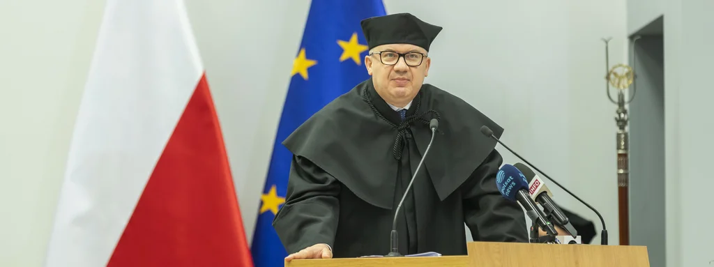 Profesor Adam Bodnar wygłasza wykład. W tle flaga Polski oraz flaga Unii Europejskiej